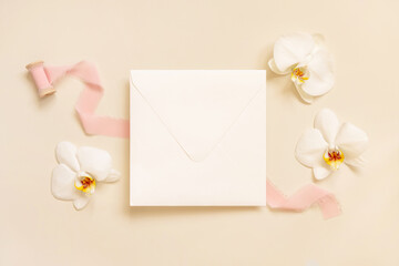Wedding envelope near white orchid flowers and silk ribbons on light yellow, suite mockup