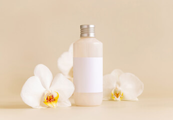 Obraz na płótnie Canvas Cosmetic bottle with blank label near white orchid flowers on light yellow, Mockup