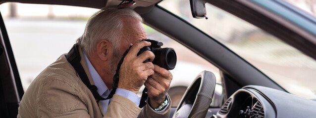 Senior man photographing with professional camera while sitting in the car