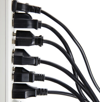 Too many electrical cords connected to a white power strip or extension block. Isolated on white.