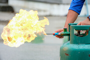 Hands of experts light gas cylinders for fire prevention drills in the workplace.