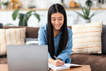 Happy female student using laptop computer, studying, distance learning. Young Asian freelancer...