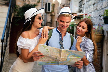 Smiling gorup of friends with map. Tourism, travel, leisure, holidays and friendship concept