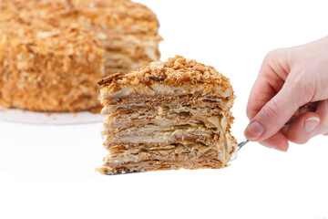 Napoleon cake, with a cut out slice on the spatula in hand, on white background isolated