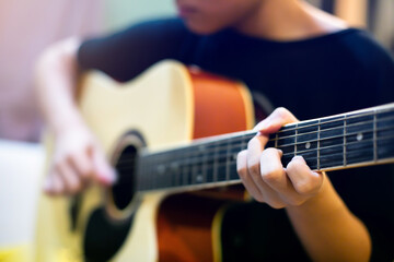 Selective focus to finger of musician playing acoustic classical guitar.