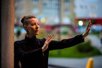 Asian woman trains tai chi in the city, chinese martial arts, healthy lifestyle concept.