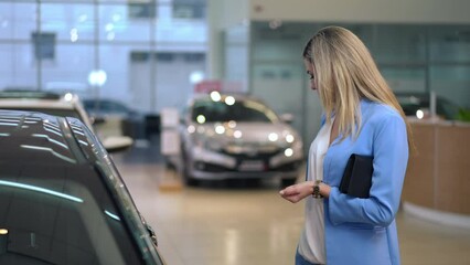 Gorgeous successful businesswoman choosing new automobile in car dealership indoors. Portrait of thoughtful Caucasian beautiful woman looking around making decision buying vehicle. Auto industry