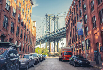 Manhattan Bridge between Manhattan and Brooklyn over East River seen from a narrow alley enclosed by two brick buildings on a sunny day in Washington street in Dumbo, Brooklyn, NYC - obrazy, fototapety, plakaty