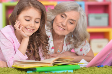 granddaughter with grandmother doing homework and reading books