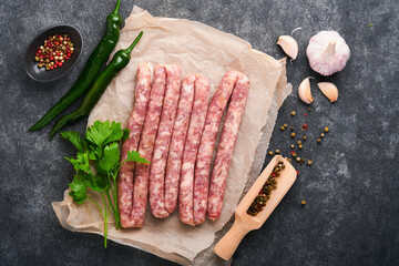 Raw sausages. Bratwurst or sausages with ingredients on cutting board with spices on a stone...