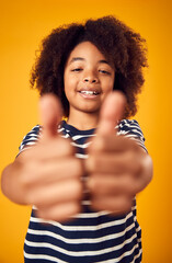 Studio Portrait Of Smiling Young Boy Making Thumbs Up Gesture Shot Against Yellow Background