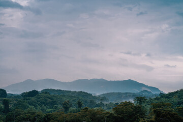 Fototapeta premium Tropical mountain range with visible silhouettes through the morning colorful fog.