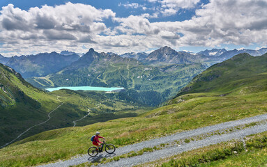 Fototapeta na wymiar nice active senior woman riding her electric mountain bike in the silvretta mountain range above barrier lake Kopssee,near Gaschurn, Tyrol, Austria 