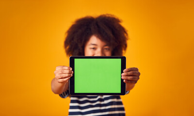 Studio Portrait Of Boy Using Digital Tablet With Green Screen Against Yellow Background