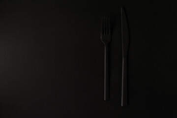 Black fork and knife on the black background.