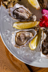 Oysters lie on a plate with ice, a knife, lemon and flower petals