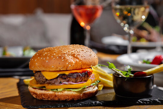 Hamburger with cutlet, cheese, tomatoes, onion, frisse salad, sesame and ketchup, sauce