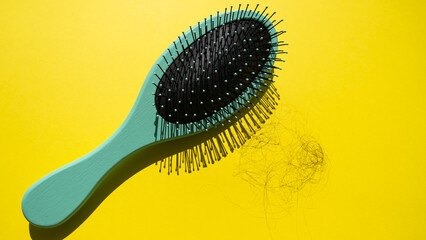 Green comb and fallen hair on the yellow background. Baldness and hair loss problem