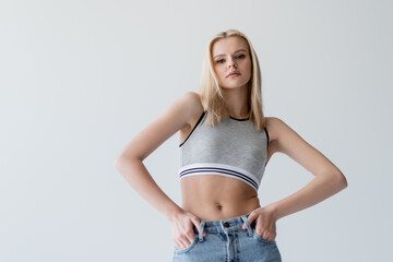 Pretty blonde woman in top posing isolated on grey.