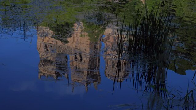 Durham Cathedral reflection in water during sunny summer day. View from river wear with lush green trees