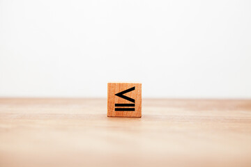 ≦の記号。小なりイコール。不等号。同じか小さい。木製ブロックに書かれている。黒い文字。木製テーブルの背景。