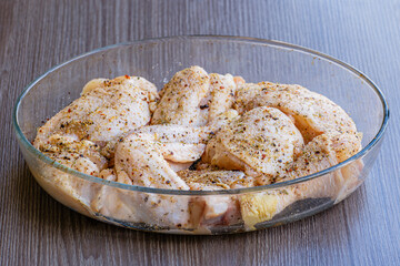 Raw pickled thighs for grilling and barbecue in glassware on a wooden table. Cooking meat. Raw chicken thighs and marinade ingredients before cooking. The concept of healthy food.