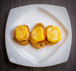 Top view of cheese sandwiches. Healthy sandwich with ham, melted cheese in a white plate on a wooden background. The concept of a quick snack. Grilled cheese sandwich. 