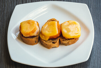 Top view of cheese sandwiches. Healthy sandwich with ham, melted cheese in a white plate on a wooden background. The concept of a quick snack. Grilled cheese sandwich. 