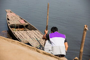 Young man getting ready to sail the wooden boat to the river. Young boy holding the paddle of the...