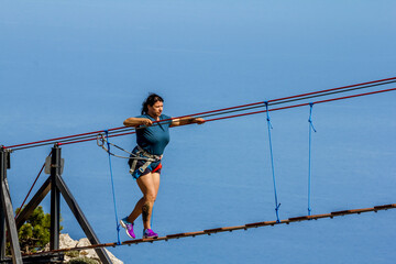 Young woman crossing a chasm on a rope bridge