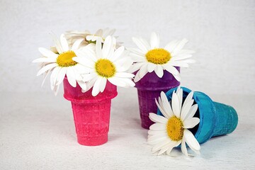 White daisies in colorful ice cream cones on paper lace doily