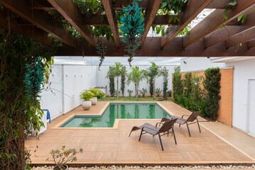 Beautiful greenish swimming pool surrounded by a garden with ornamental plants such as the Jade...