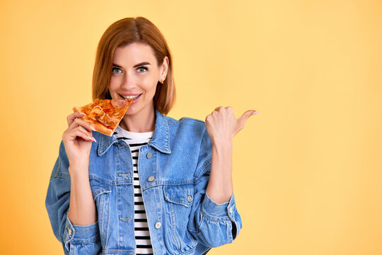 Young Woman Eating Pizza Slice And Looking Delighted