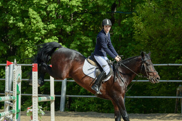 A young woman performs a sports race on a horse on a sunny summer day.