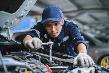 Portrait of an Asian mechanic checking the safety of a car. Maintenance of damaged parts in the...