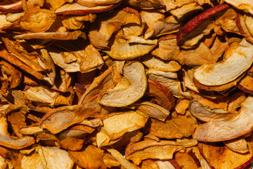 Background of dried apple slices. Dried slices of apples finely chopped for the preparation of healthy drinks, fruit drinks and compotes. Dried apple chips background selective focus top view.