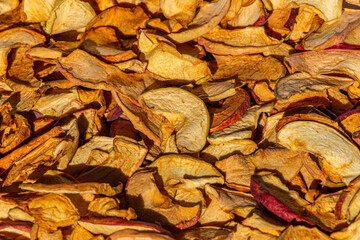 Background of dried apple slices. Dried slices of apples finely chopped for the preparation of healthy drinks, fruit drinks and compotes. Dried apple chips background selective focus top view.