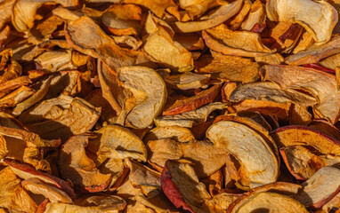 Background of dried apple slices. Dried slices of apples finely chopped for the preparation of healthy drinks, fruit drinks and compotes. Dried apple chips background selective focus top view.