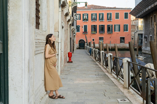 Side view of pregnant woman standing near old building on street in Venice.