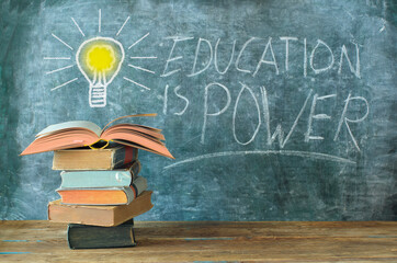 books and blackboard with drawing of a lightbulb and slogan education is...