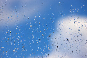 Water drops on a dusty windshield with defocused cloud and sky background