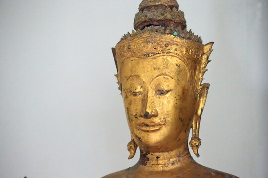 The head of an ancient Buddha statue was made of gold, image on copy space white background.