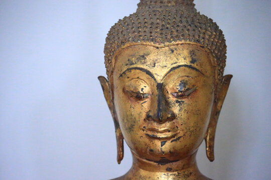 The head of an ancient Buddha statue was made of gold, image on copy space white background.