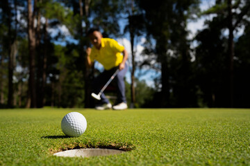 Golfer putting ball on the green golf, lens flare on sun set evening time.