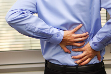 Obraz premium Business man wearing blue shirt feels back pain. Healthcare and medical concept.