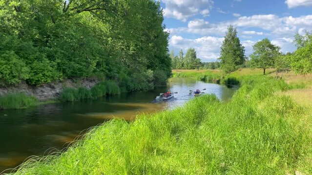 A group of tourists in two-person kayaks rafting in the summer on the river.