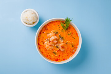 Tom Yam soup with shrimp on blue background top view