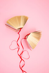 Old books and red ribbons on pastel pink  background. Education, knowledge or nature concept. Flat...