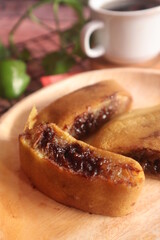 Sweet chocolate flavored martabak served on a wooden plate and accompanied by a glass of warm tea