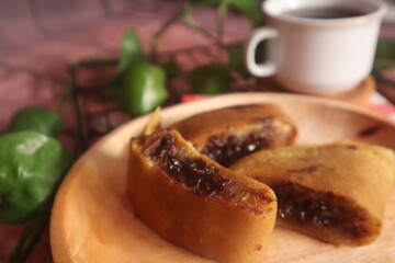 Sweet chocolate flavored martabak served on a wooden plate and accompanied by a glass of warm tea
